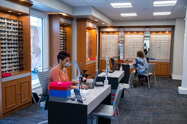 Staff member working on laptop in front of glasses display case